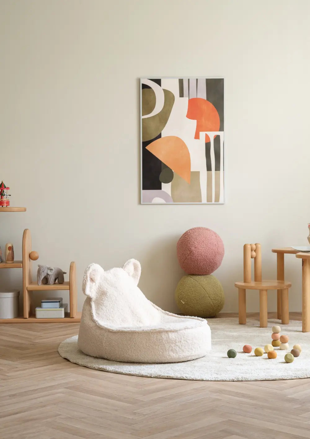 Der cremeweiße Wigiwama Bären Sitzsack Cream Teddy White steht auf einem runden Teppich in einem geschmackvoll eingerichteten Kinderzimmer.
