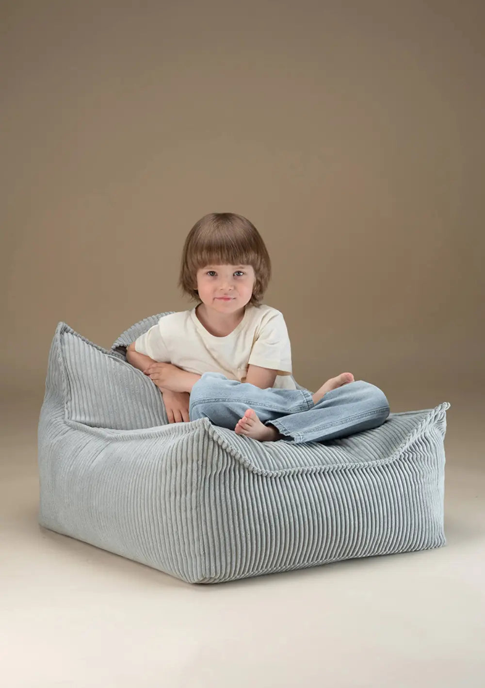 Ein Kind sitzt im Schneidersitz entspannt im minzgrünen Wigiwama Sitzsack Cord Peppermint Green aus Breitcord.