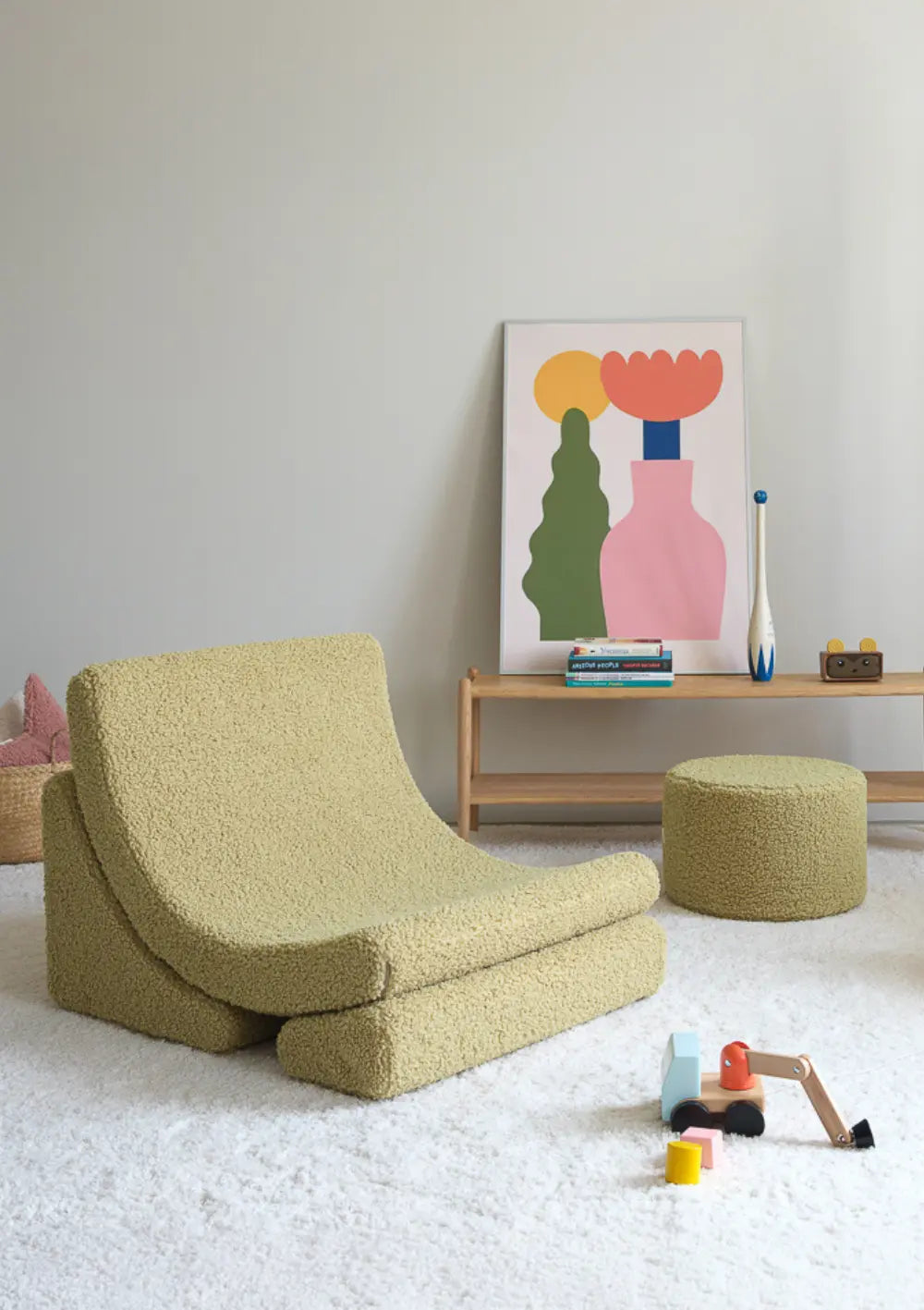 Der stilvolle Wigiwama Kindersessel Moon Chair Teddy Matcha in Matcha-Grün steht freistehend neben einem passenden Pouf in einem hellen Kinderzimmer.