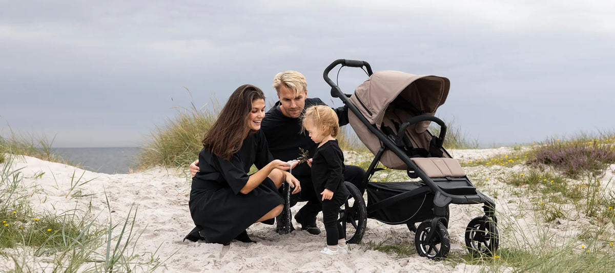 Thule Urban Glide - im Bild: Thule Urban Glide 4-wheel Kinderwagen mit Eltern und Kind am Strand
